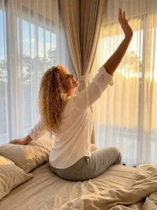 a girl stretching in morning sunlight by a window to increase energy level