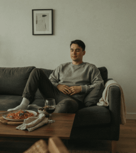 person resting on a couch shortly after a meal, looking relaxed rather than distressed