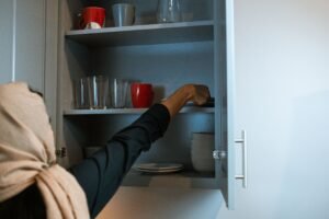 person organizing a kitchen cabinet into labeled zones