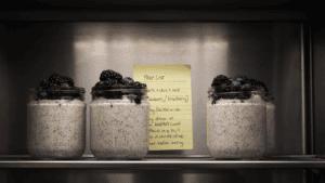 Three glass jars of overnight oats with chia seeds and berries lined up in a fridge | Place after the night-before prep list